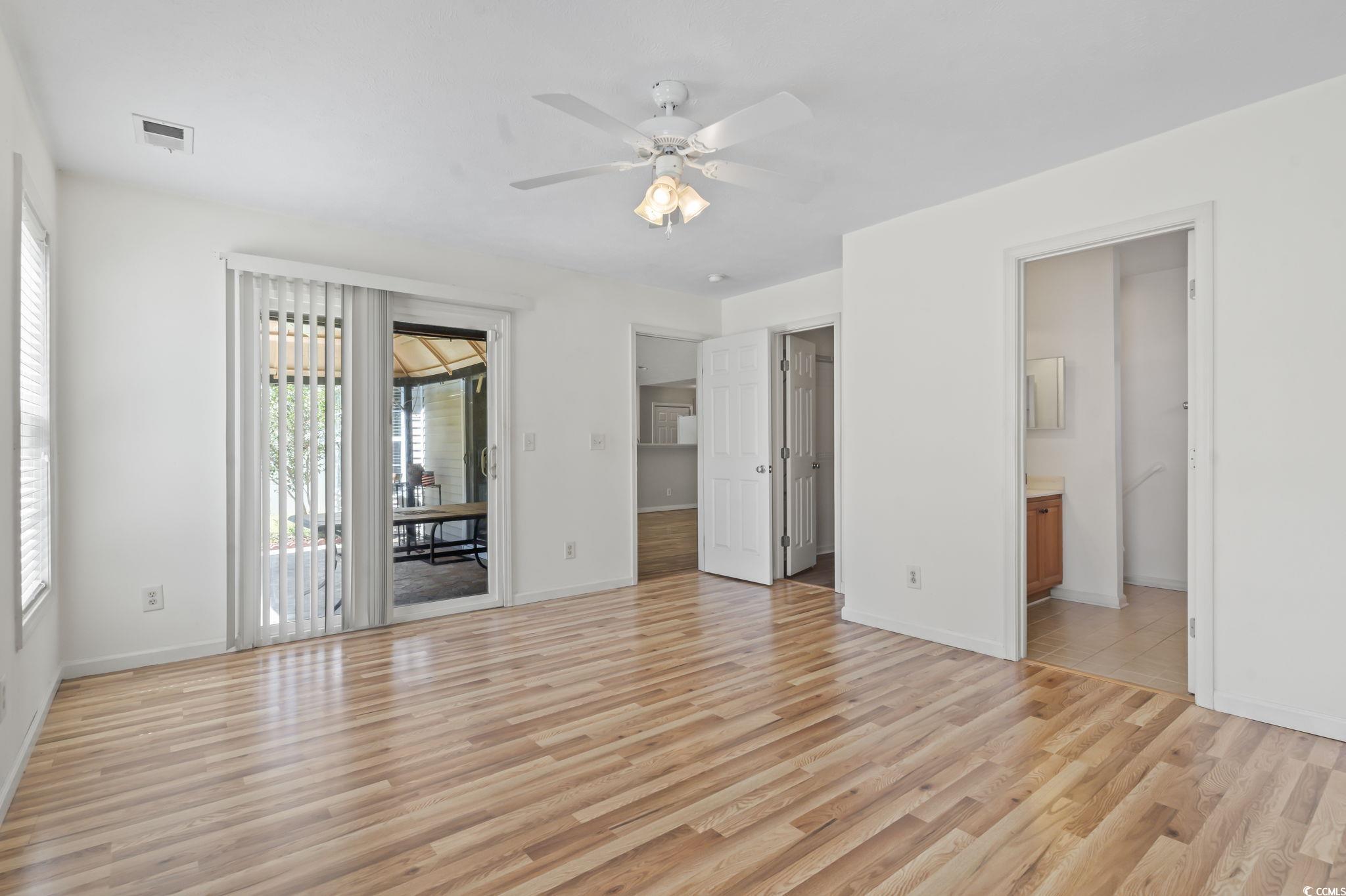 717 West Perry Road Myrtle Beach, SC 29579 - Photo 14 of 29 Unfurnished owner's bedroom featuring light wood finished floors, access to outside, a ceiling fan and ensuite bathroom