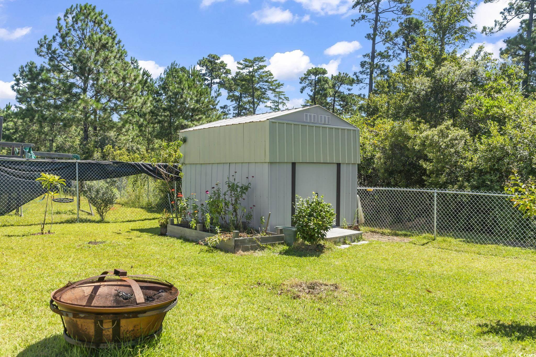 717 West Perry Road Myrtle Beach, SC 29579 - Photo 26 of 29 Fenced backyard with an outdoor fire pit, a storage shed, and a garden