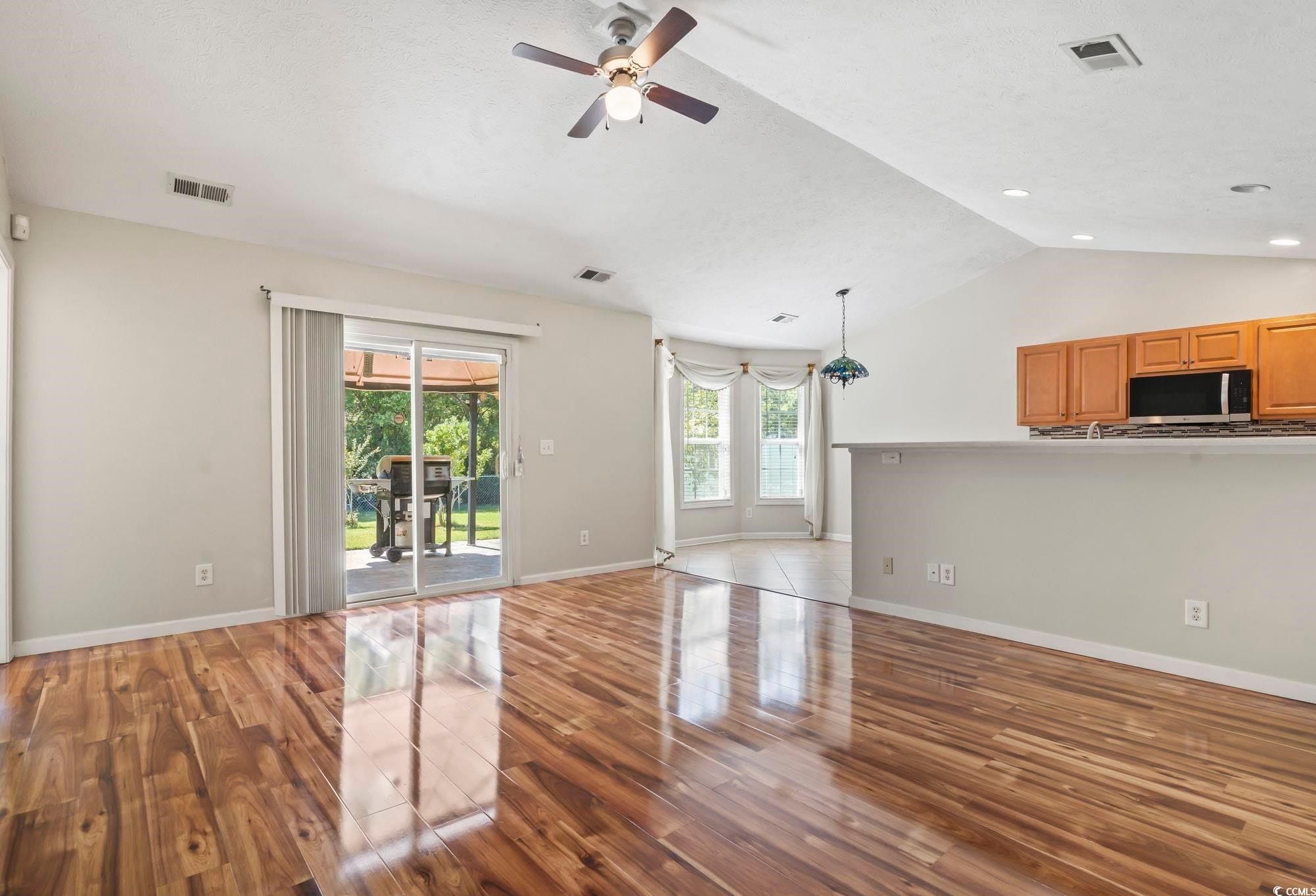717 West Perry Road Myrtle Beach, SC 29579 - Photo 4 of 29 Unfurnished living room featuring lofted ceiling, wood finished floors, and ceiling fan