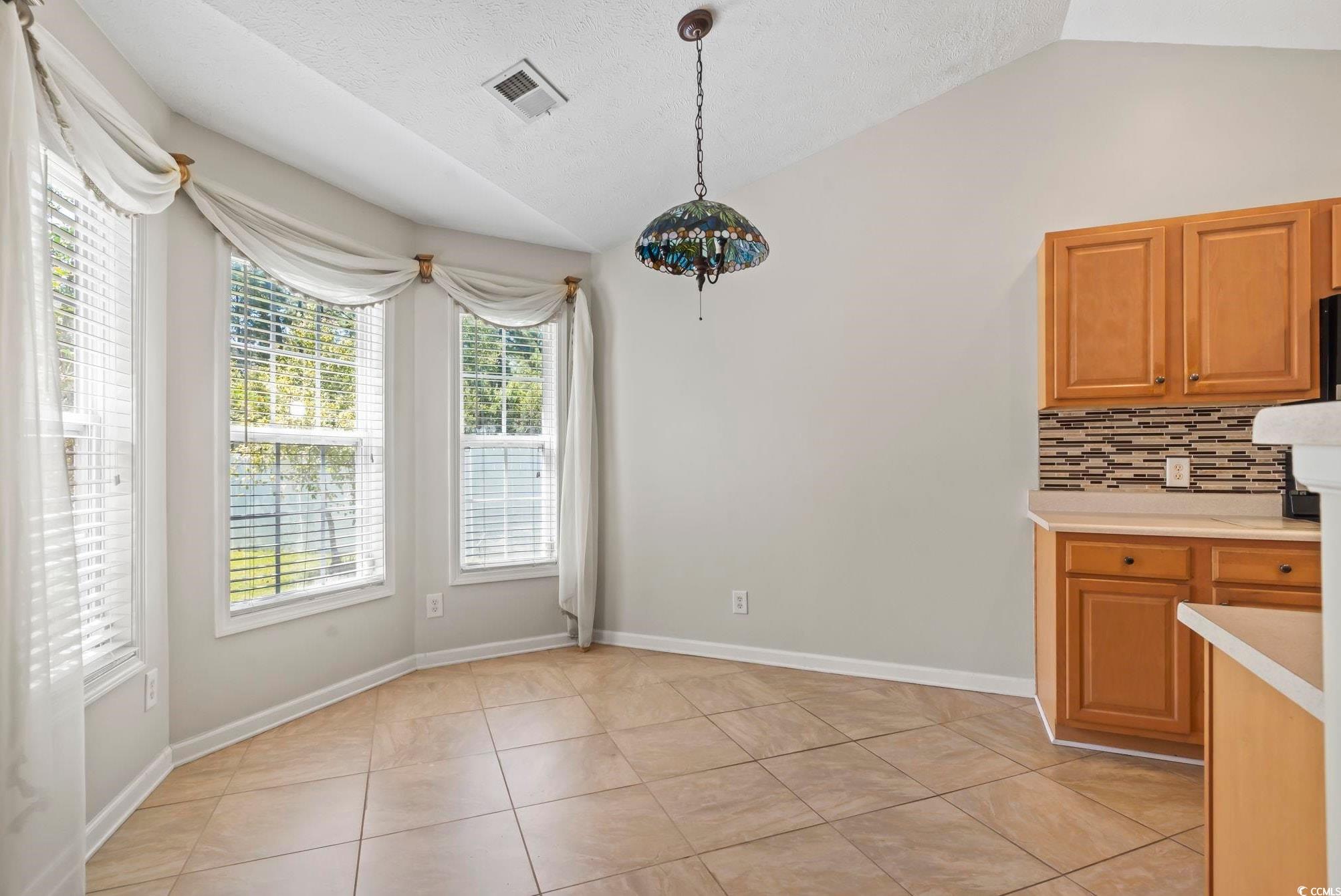 717 West Perry Road Myrtle Beach, SC 29579 - Photo 5 of 29 Unfurnished dining area featuring lofted ceiling, light tile patterned flooring, and a textured ceiling