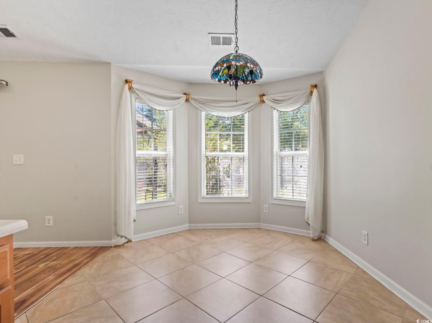 717 West Perry Road Myrtle Beach, SC 29579 - Photo 9 of 29 Unfurnished dining area with a textured ceiling, light tile patterned flooring, and lofted ceiling