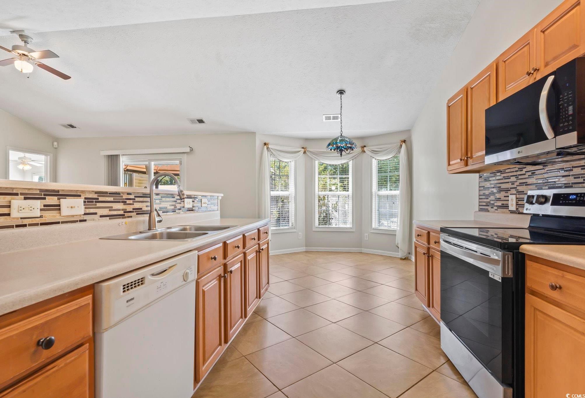717 West Perry Road Myrtle Beach, SC 29579 - Photo 10 of 29 Kitchen with backsplash, appliances with stainless steel finishes, light countertops, light tile patterned floors, and ceiling fan