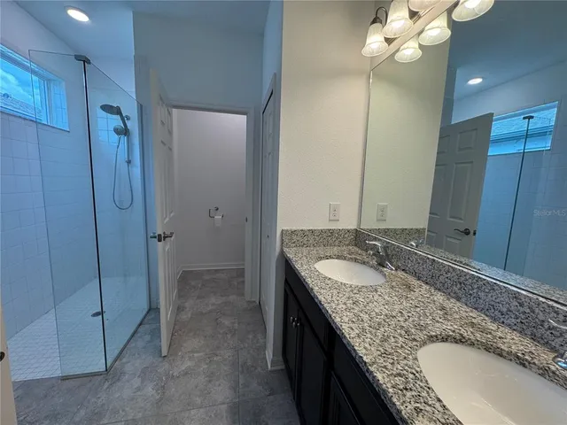 a bathroom with a granite countertop sink a mirror and shower
