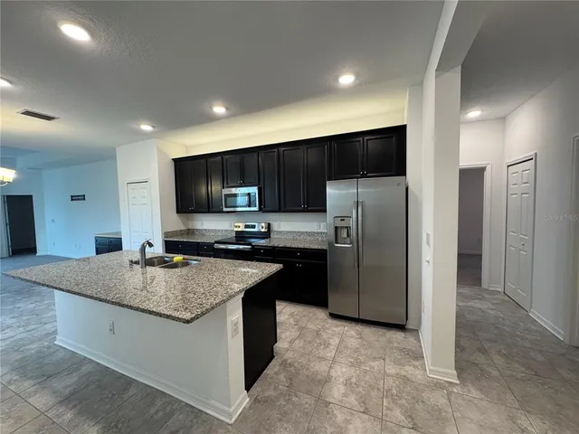 a kitchen with stainless steel appliances granite countertop a sink refrigerator and microwave
