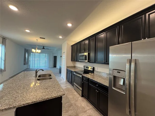 a kitchen with stainless steel appliances granite countertop a refrigerator a stove and a sink