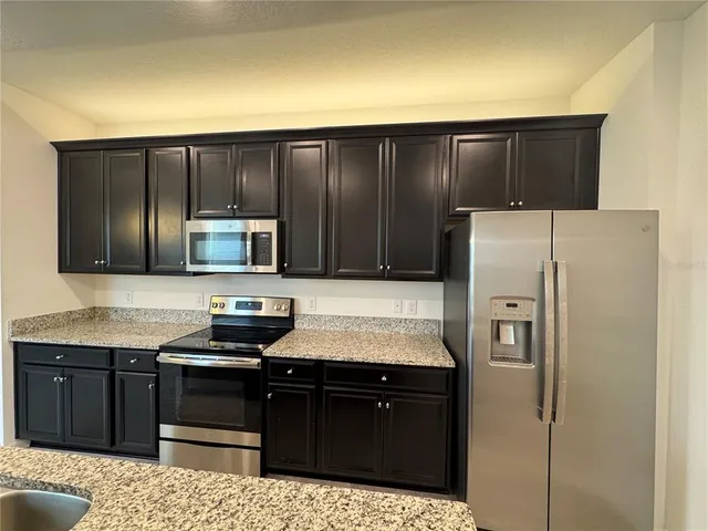 a kitchen with stainless steel appliances granite countertop a refrigerator and a stove top oven