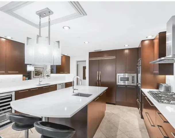 a large kitchen with kitchen island a counter space a sink stainless steel appliances and cabinets