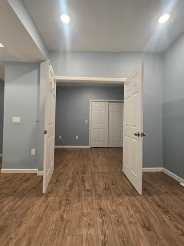 an empty room with wooden floor & closet area