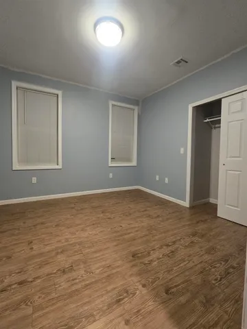 a view of an empty room with window and wooden floor
