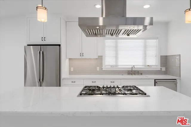 a kitchen with stainless steel appliances kitchen island granite countertop a stove a refrigerator and a sink with wooden floor