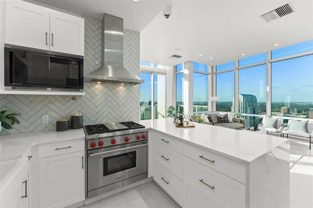 a open kitchen with stainless steel appliances a stove a sink and a microwave