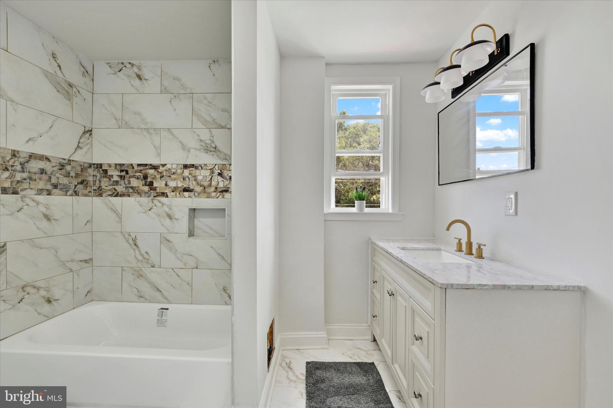 2400 West Lafayette Avenue Baltimore, MD 21216 - Photo 19 of 33 a bathroom with a granite countertop sink a mirror a bathtub and a window