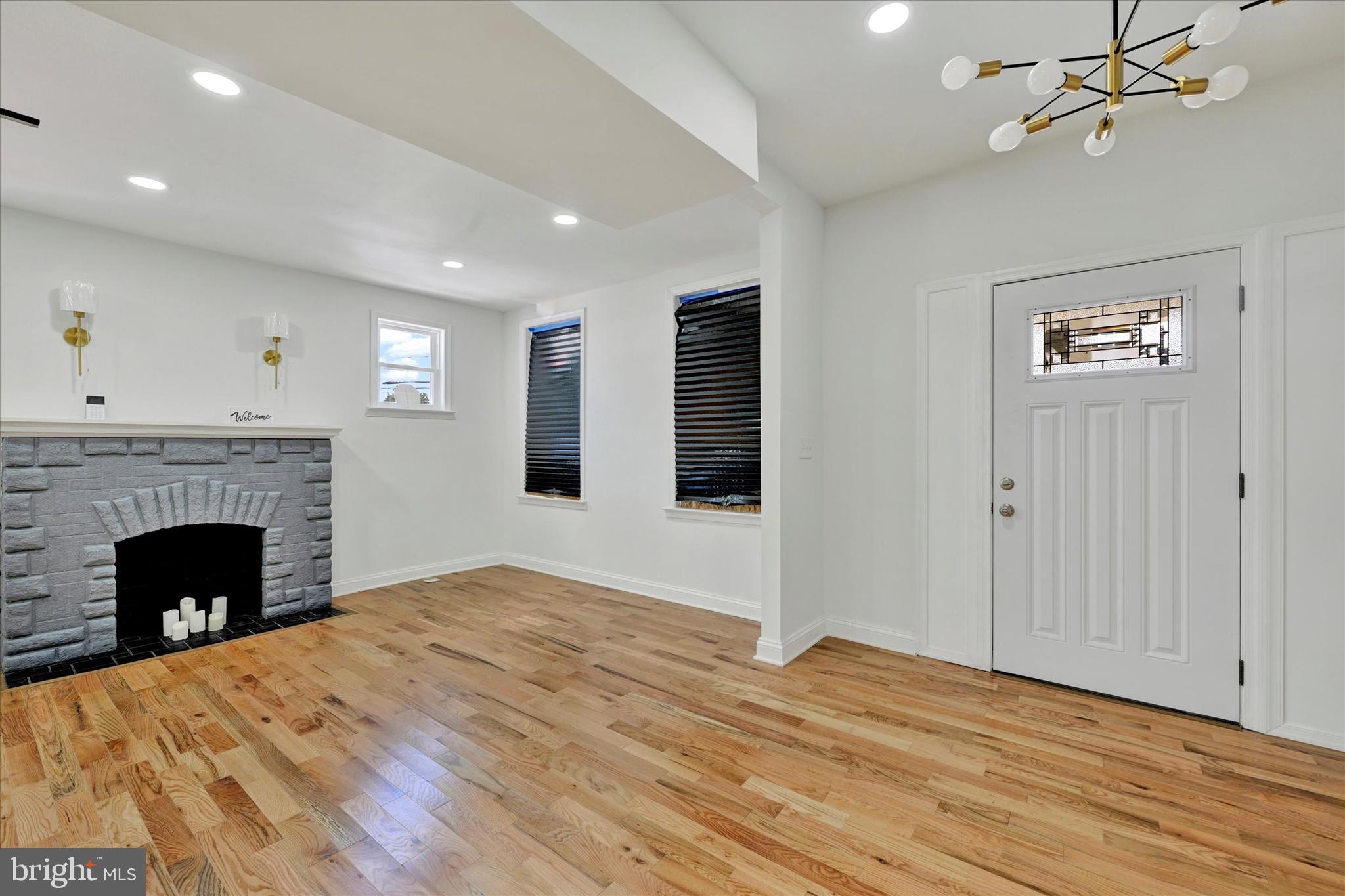 2400 West Lafayette Avenue Baltimore, MD 21216 - Photo 4 of 33 a view of an empty room with wooden floor fireplace and a window