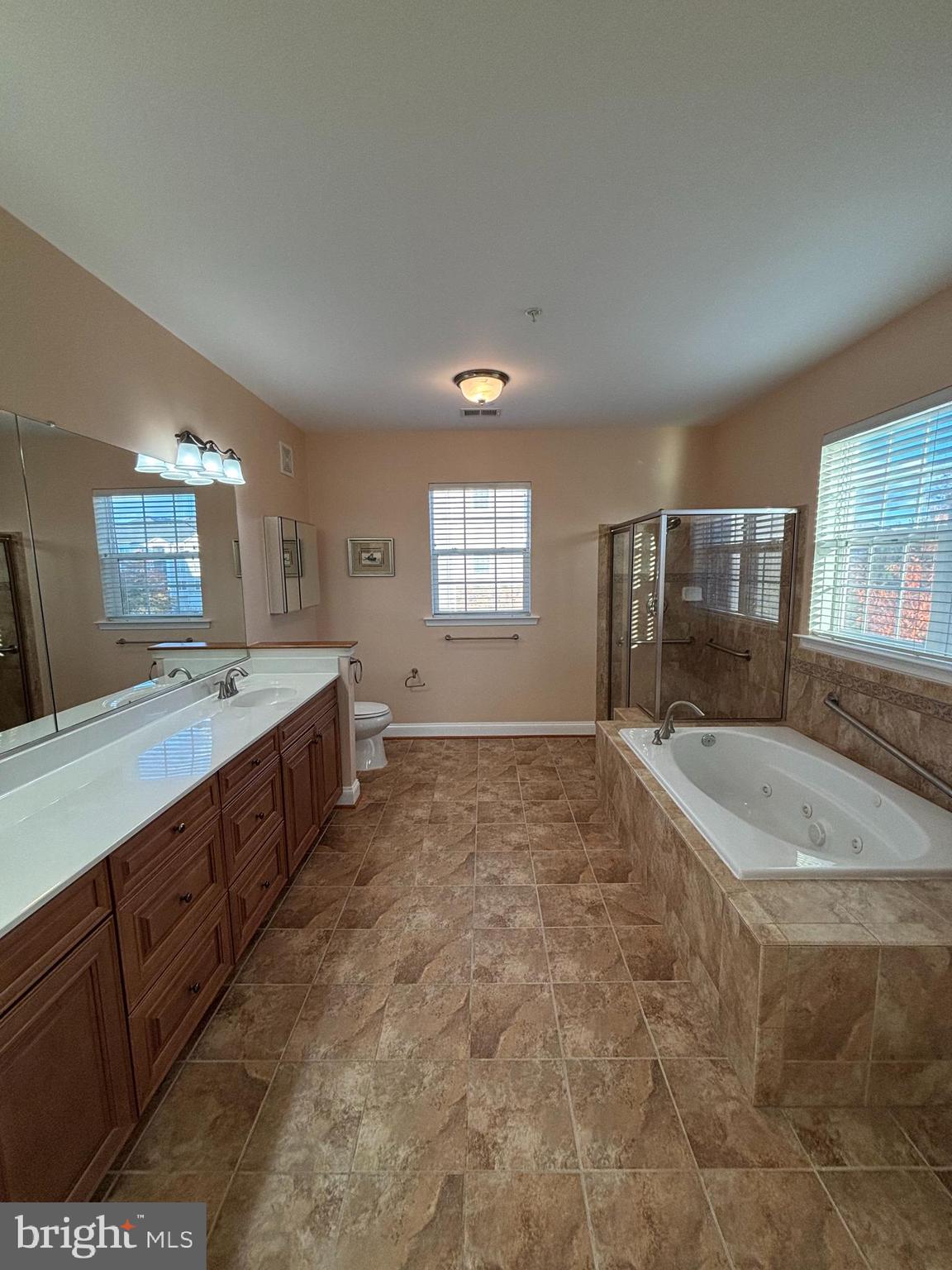 7300 Travertine Drive, Unit 302 Baltimore, MD 21209 - Photo 12 of 19 a spacious bathroom with a granite countertop sink a mirror and a bathtub