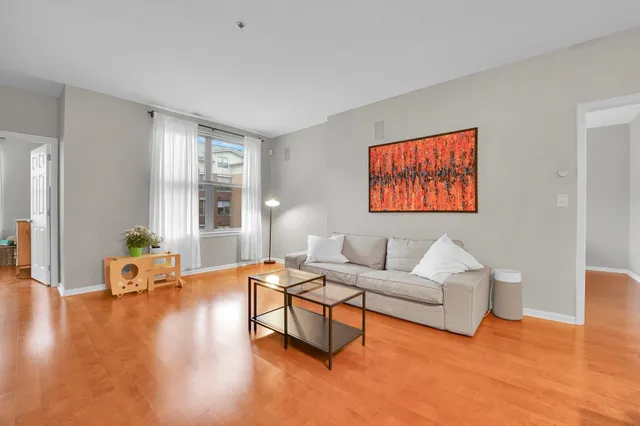 a living room with furniture and a dining table with wooden floor