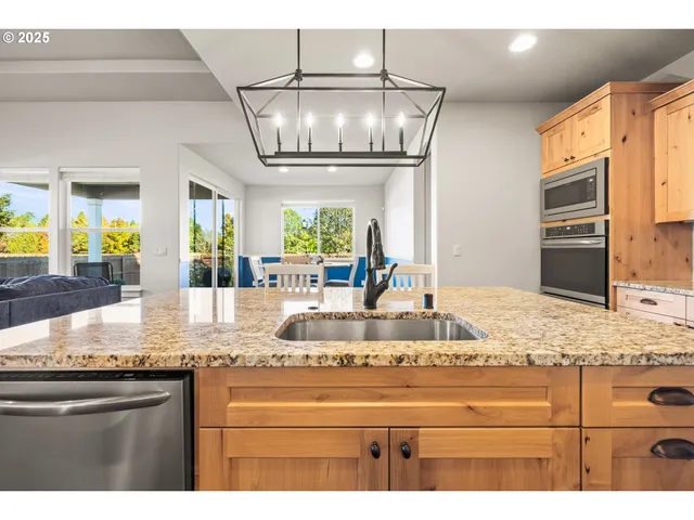 a kitchen with stainless steel appliances granite countertop a sink a stove and a wooden floors
