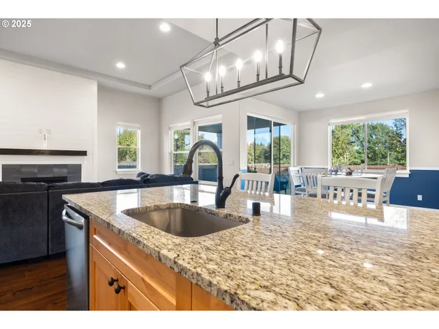 a kitchen with stainless steel appliances granite countertop a table chairs and a refrigerator