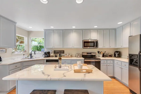 a kitchen with kitchen island a counter space a sink appliances and cabinets