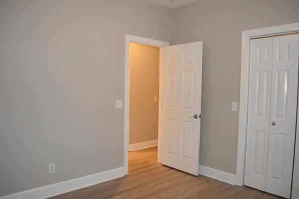 an empty room with wooden floor and closet area