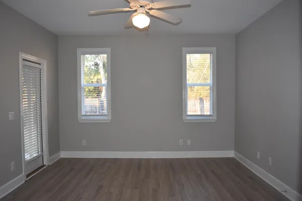a view of an empty room with wooden floor and a window