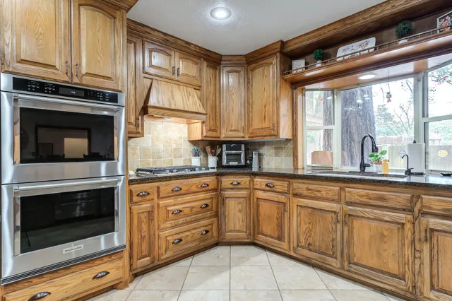 a kitchen with granite countertop white cabinets stainless steel appliances a sink and a window