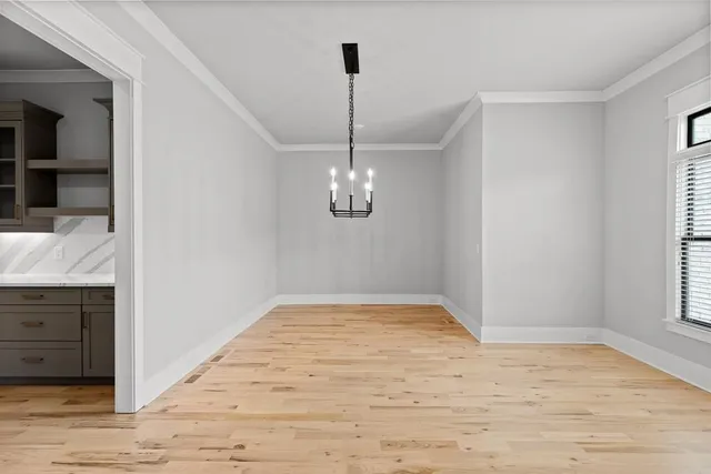 a view of empty room with wooden floor and kitchen view