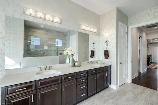a spacious bathroom with a granite countertop double vanity sink a mirror a vanity and shower