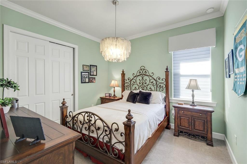 9075 Breakwater Drive Naples, FL 34120 - Photo 20 of 48 a bedroom with a bed and a chandelier