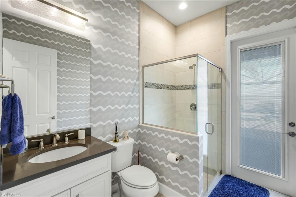 9075 Breakwater Drive Naples, FL 34120 - Photo 23 of 48 a bathroom with a granite countertop sink toilet a mirror and shower
