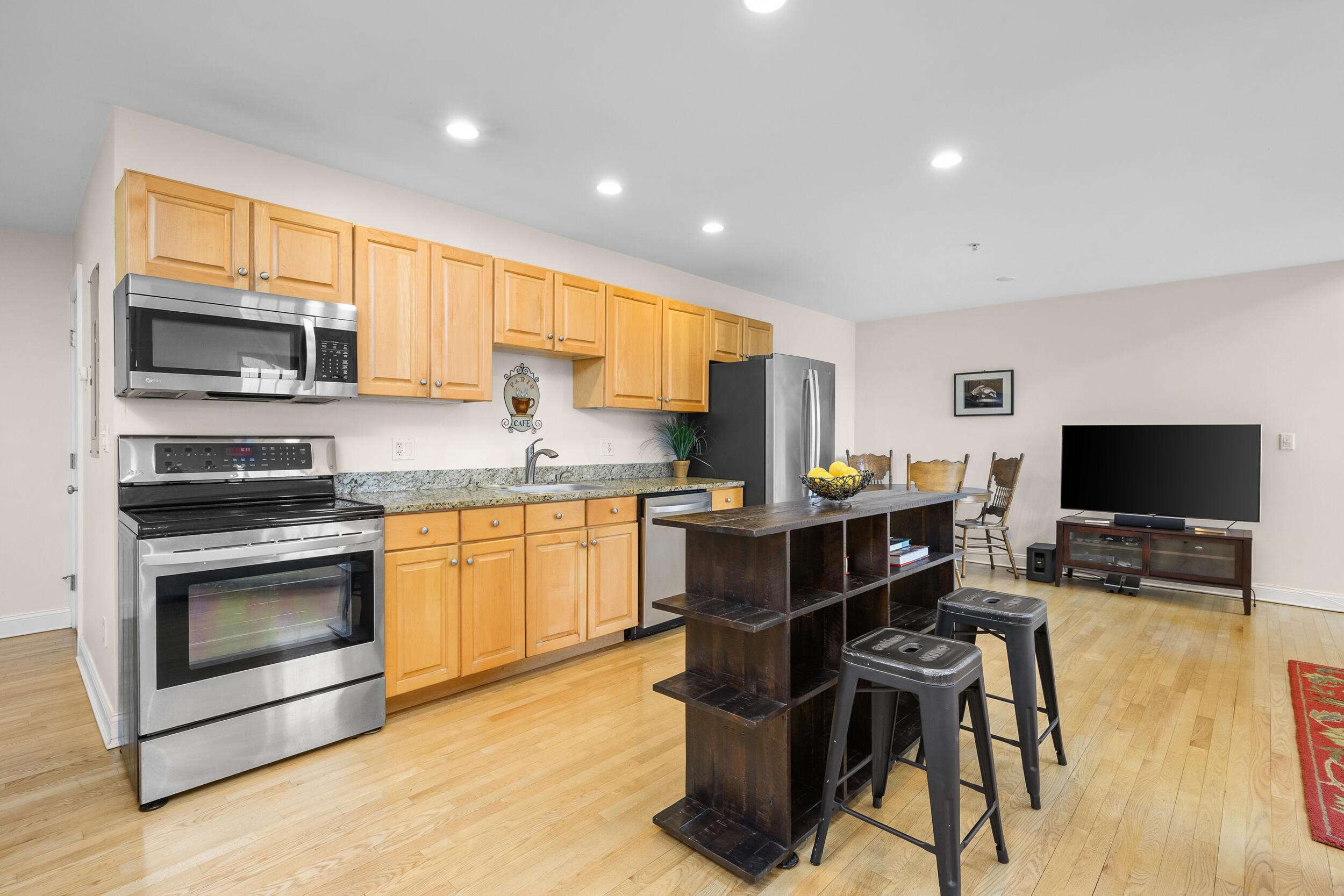 615 Main Street, Unit 3 Hyannis, MA 02601 - Photo 4 of 22 a open kitchen with stainless steel appliances granite countertop a stove top oven a sink dishwasher a dining table and chairs with wooden floor