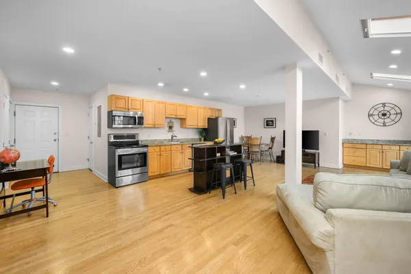 a living room filled with stainless steel appliances kitchen island granite countertop furniture and a dining table with wooden floor