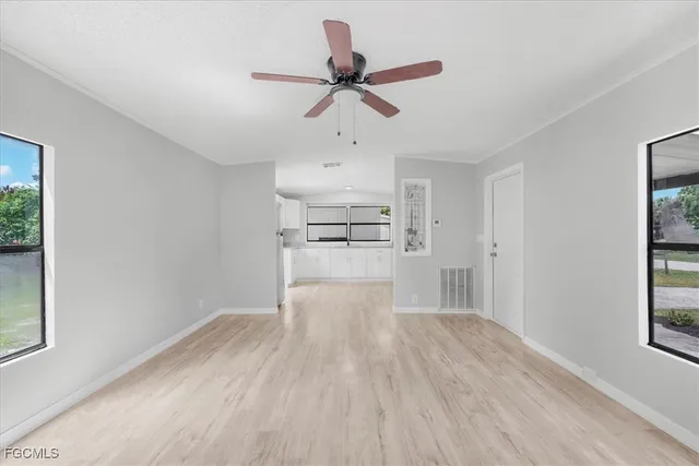 a view of empty room with wooden floor and ceiling fan