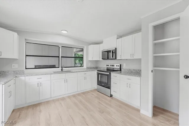 a kitchen with granite countertop white cabinets and window