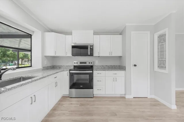 a kitchen with granite countertop white cabinets and stainless steel appliances
