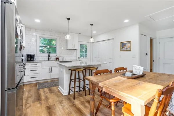 a kitchen with stainless steel appliances kitchen island granite countertop a stove a sink a dining table and chairs