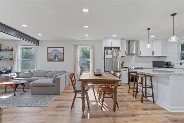 a living room with stainless steel appliances kitchen island granite countertop furniture and a wooden floor