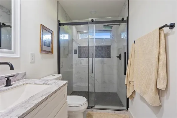 a bathroom with a granite countertop sink toilet and shower