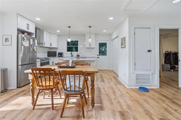 a dining room with stainless steel appliances kitchen island granite countertop a refrigerator a stove a sink with a dining table and chairs