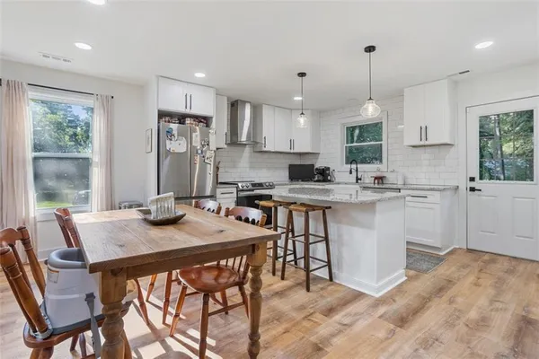 a kitchen with stainless steel appliances kitchen island granite countertop a sink a stove a kitchen island with a dining table and chairs