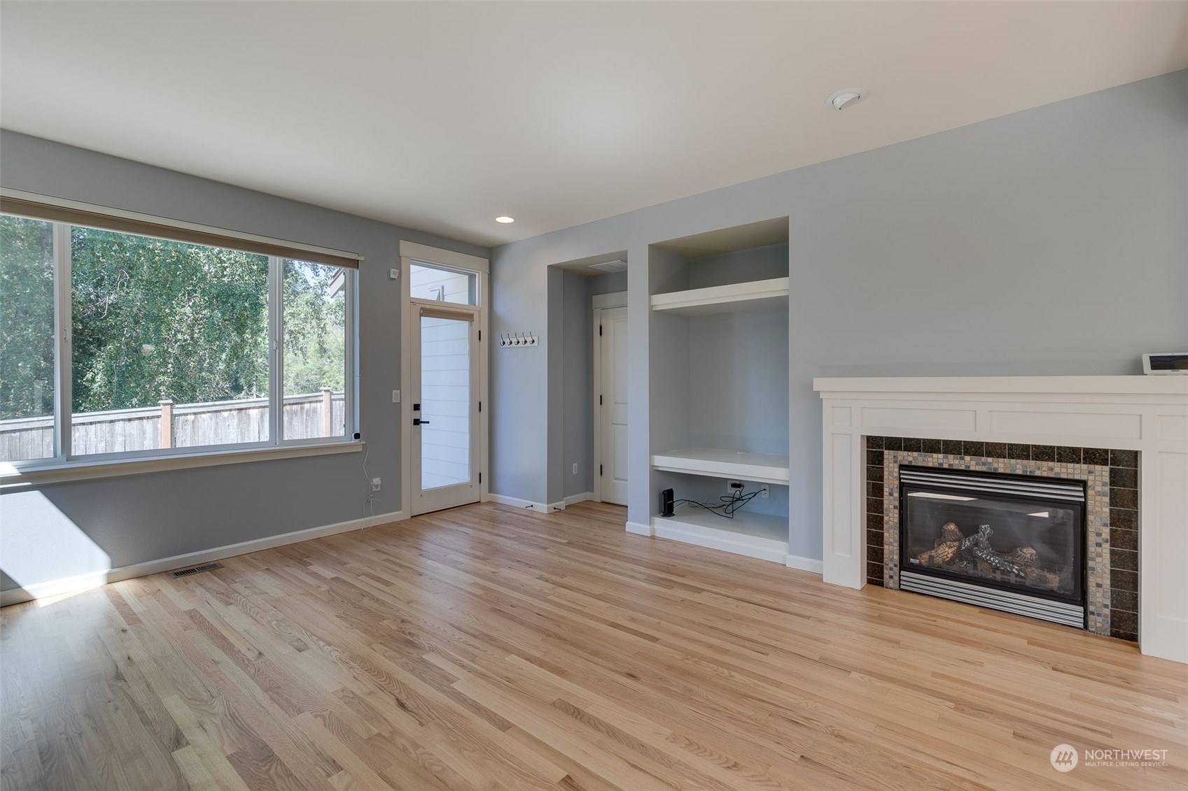 571 Lyons Place Northeast Renton, WA 98059 - Photo 11 of 27 an empty room with wooden floor fireplace and windows