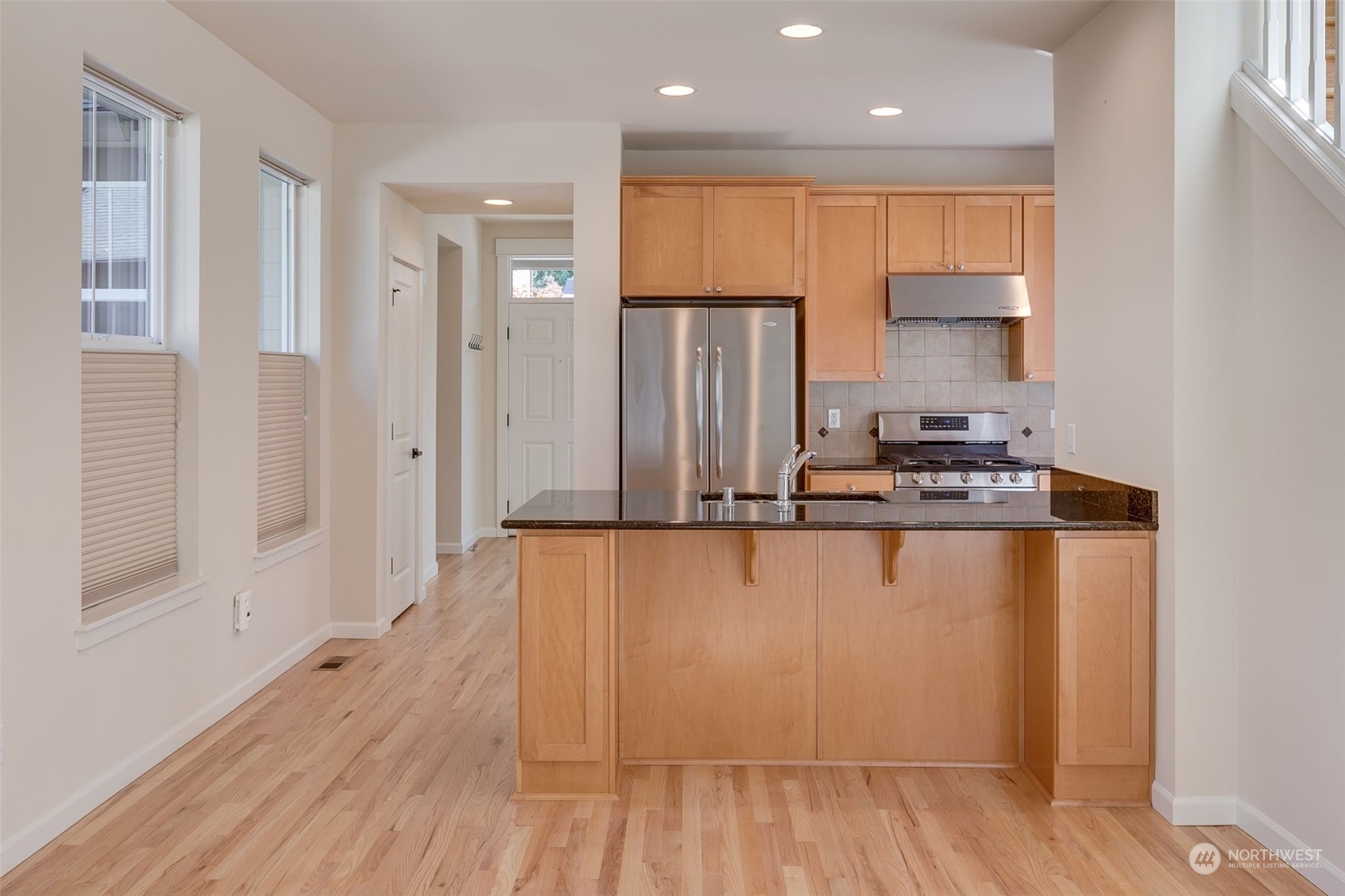 571 Lyons Place Northeast Renton, WA 98059 - Photo 6 of 27 a kitchen with stainless steel appliances granite countertop a refrigerator a sink and white cabinets with wooden floor
