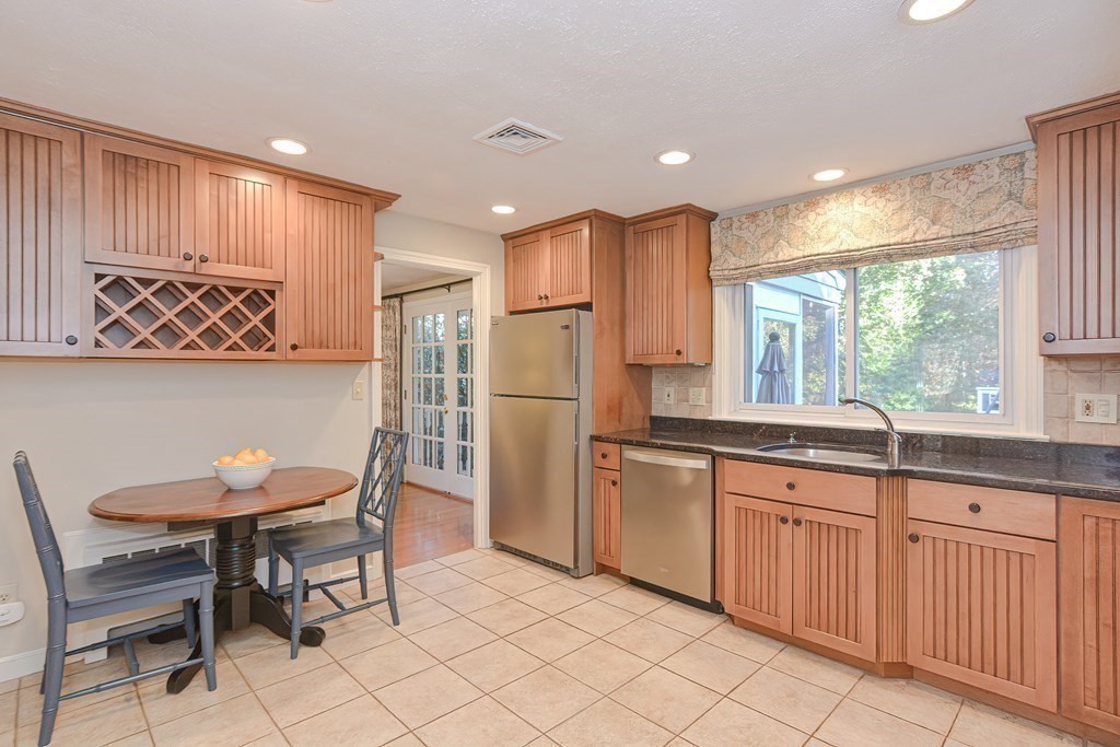 7 Tamarack Road Medfield, MA 02052 - Photo 11 of 33 a kitchen with stainless steel appliances granite countertop white cabinets dining table and chairs
