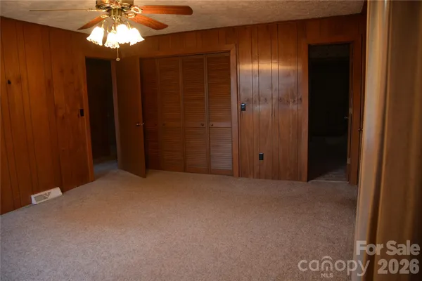 an empty room with windows and chandelier fan