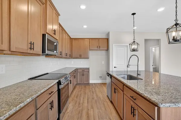 a kitchen with stainless steel appliances granite countertop a sink a stove and a wooden floors