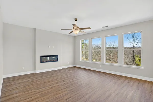 a view of an empty room with a window and wooden floor