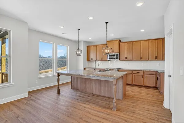 a kitchen with stainless steel appliances granite countertop wooden floors wooden cabinets a window and a sink