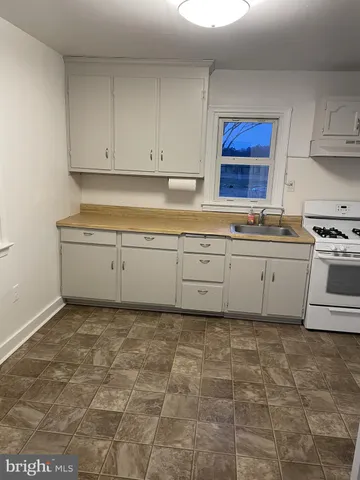a kitchen with granite countertop a sink a stove top oven and cabinets