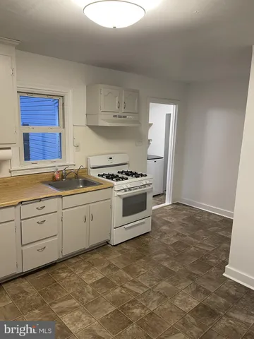 a kitchen with granite countertop a stove a sink and a refrigerator