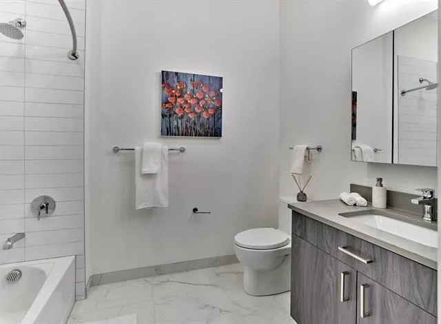 a bathroom with a granite countertop toilet a sink and a bathtub