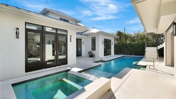 a view of a white house with large windows and a small yard